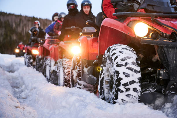 gruppo di persone che guidano quad su strada innevata. - off road vehicle 4x4 snow driving foto e immagini stock