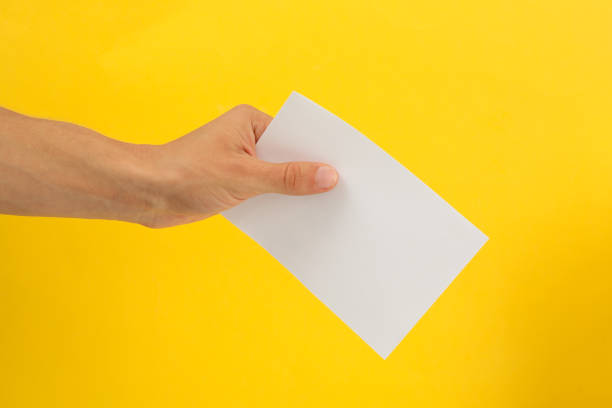 istock Male hand holding blank paper on yellow background 1267315848