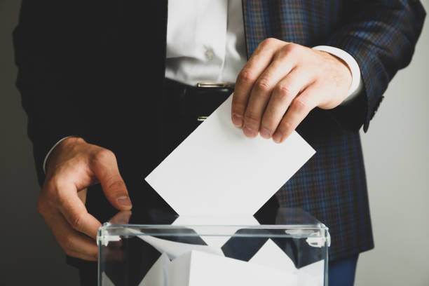 istock Man putting ballot into voting box against gray background 1267315903