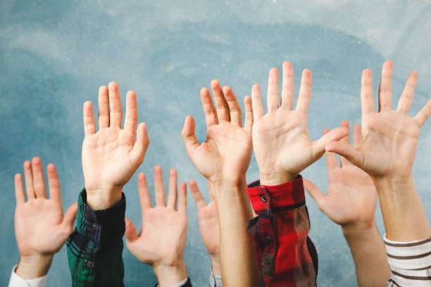 istock Hands of different people raised up on blue background 1267316127