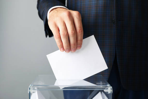 istock Man putting ballot into voting box against gray background 1267316173