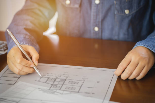 istock Architect or engineer holding pen pointing construction project equipment on the desk with a blueprint in the office. 1267321206