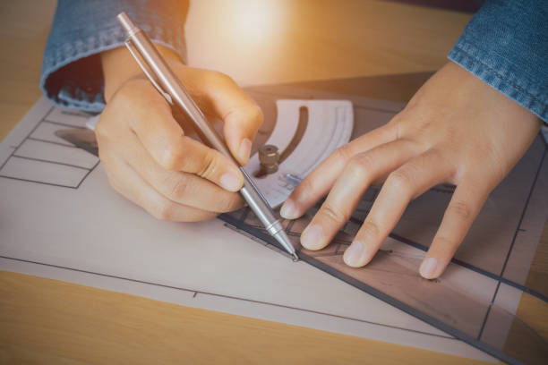 istock Architect or engineer holding a pen, measuring with a triangular ruler, and renovating a house construction project on a desk. 1267321299