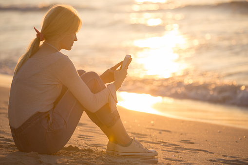 https://media.istockphoto.com/id/1267321721/photo/relaxed-young-woman-using-her-mobile-phone-to-text-at-the-beach-during-sunset.jpg?b=1&s=170667a&w=0&k=20&c=6mc4OLHmIONKT5xjaP1uAAY44nZMEHpeiPXfXXU90jI=