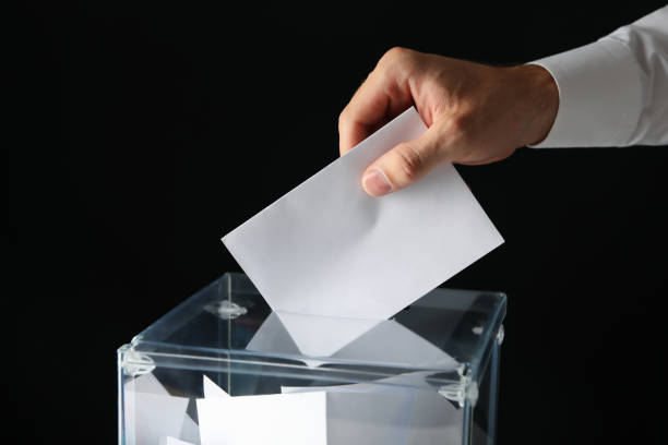 istock Man putting ballot into voting box on black background 1267323512