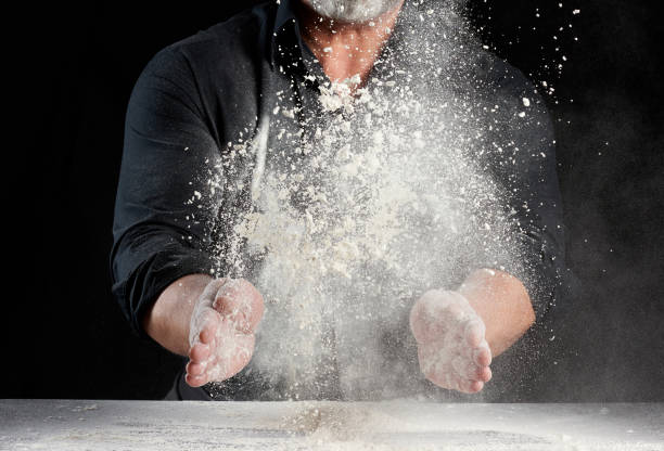 istock chef in black uniform sprinkles white wheat flour in different directions, product scatters dust 1267324677