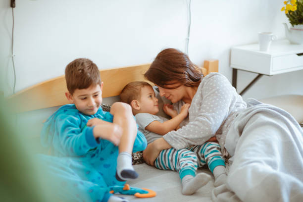 istock Mother in bed with her sons, showing affection to toddler 1267324757