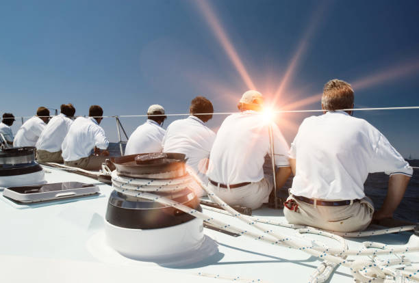 vista posteriore dell'equipaggio a vela con bagliore dell'obiettivo - sailing sailboat regatta teamwork foto e immagini stock