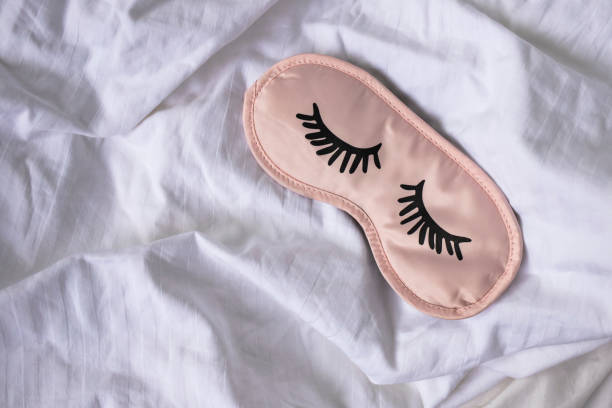 Sleep mask on white bedding. Healthy sleep concept.