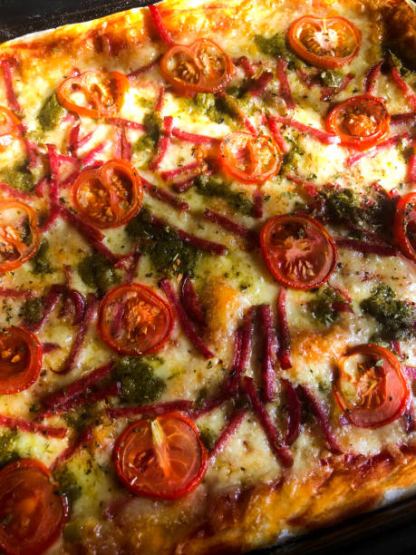 istock Baked pizza with salami, tomatoes and pesto 1267333492