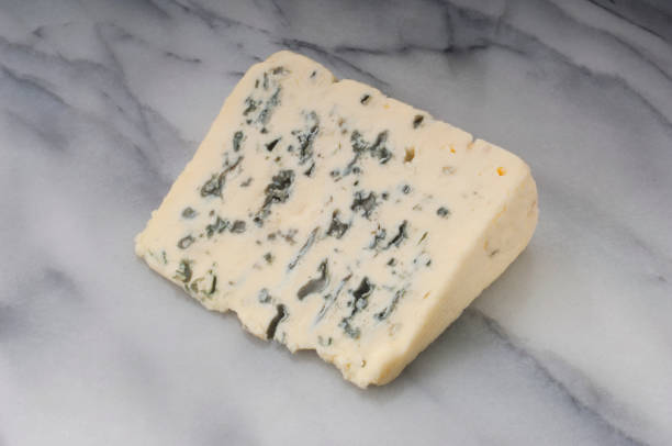 Blue Cheese on Marble Studio shot of a slice of blue cheese resting on a marble slab. roquefort cheese stock pictures, royalty-free photos & images