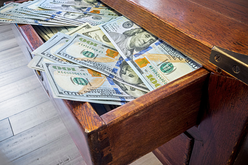 Looking down on wooden desk with 100 dollar bills