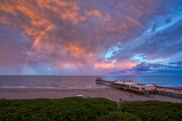 The Cocoa Beach Pier During a Vibrant Sunset with a Rainbow at Cocoa Beach in Central Florida USA The Cocoa Beach Pier during sunset at Cocoa Beach in Central Florida USA cocoa beach stock pictures, royalty-free photos & images
