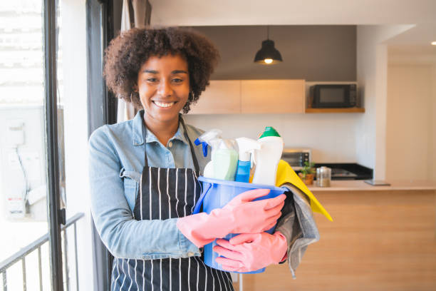 istock Afro woman holding a bucket with cleaning items. 1267345323