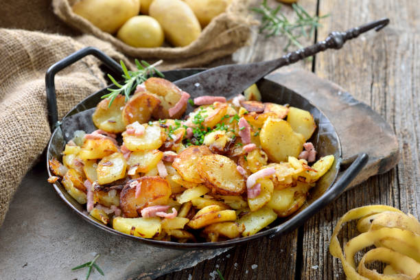 Fried potatoes Hearty fried potatoes with onions and bacon served in an iron pan with rustic ambience fried potato stock pictures, royalty-free photos & images