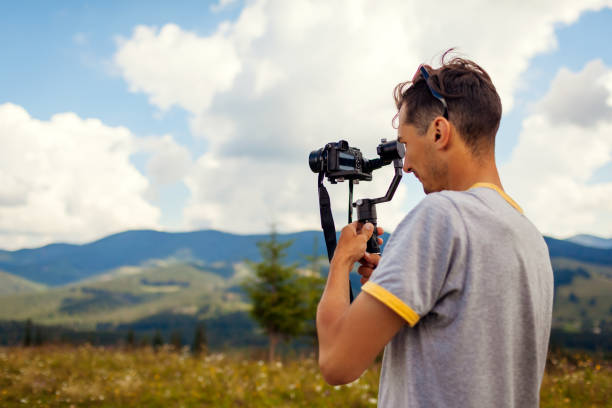 istock Videographer filming Carpathian mountains landscape. Man using steadicam and camera to make footage. Video shoot 1267348229