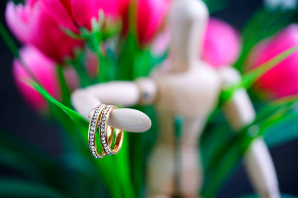 istock Wooden figure holding two golden wedding ring 1267348519