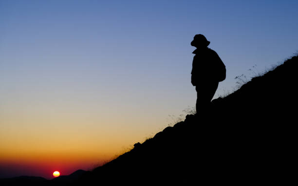istock Mountain climber silhouette man on steep slope at sunrise 1267349024