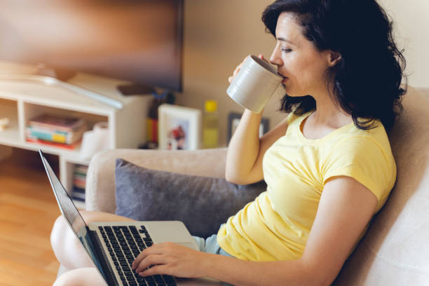 istock Nice beautiful lady with black curly hair work at the notebook sit down on the sofa at home - check on online shops for cyber Monday sales - technology woman concept for alternative office freelance 1267349831