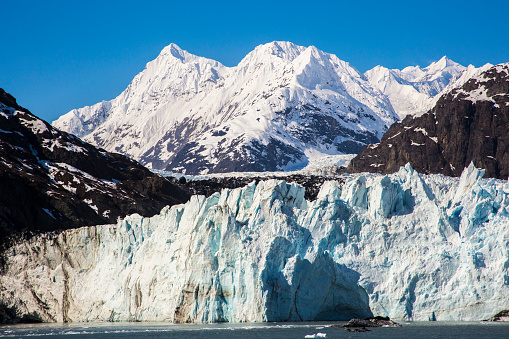 Glacier Bay Alaska cruise vacation travel. Global warming and climate change concept with melting ice. Cruising boat towards landscape of Johns Hopkins Glacier and Mount Fairweather Range mountains.