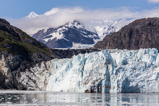 Glacier Bay Alaska cruise vacation travel. Global warming and climate change concept with melting ice. Cruising boat towards landscape of Johns Hopkins Glacier and Mount Fairweather Range mountains.