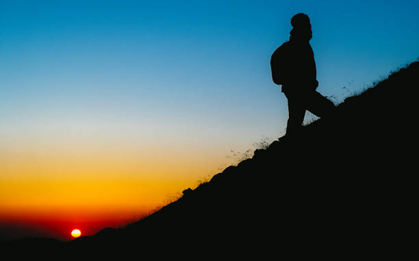 istock Mountain climber silhouette man on steep slope at sunrise 1267350093