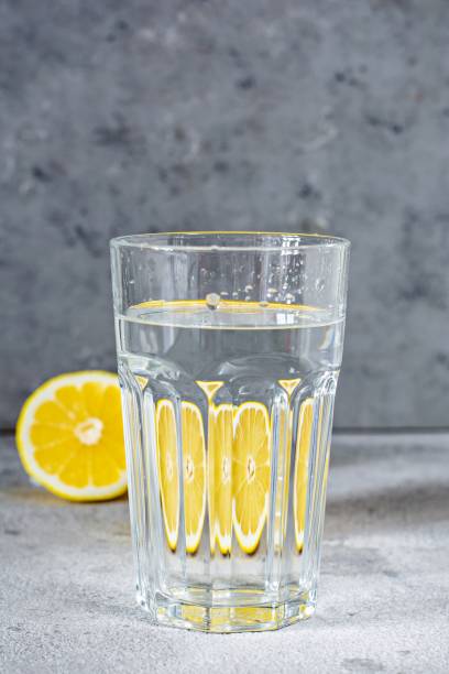 istock Shooting through glass objects with water. Orange (lemon) reflecting through a glass cup with water on a gray background. 1267351403