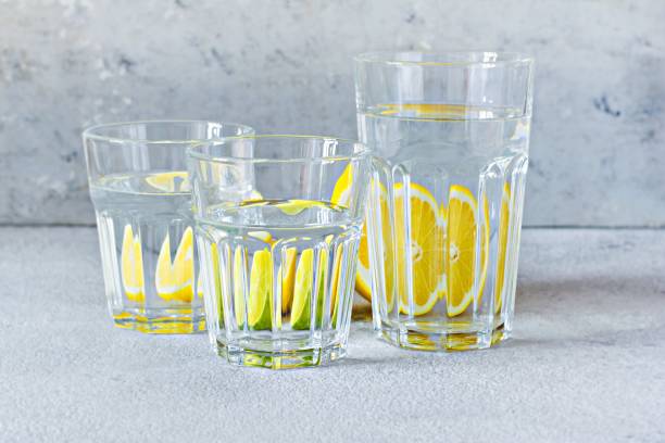 istock Shooting through glass objects with water. Orange (lemon) reflecting through a glass cup with water on a gray background. 1267351408