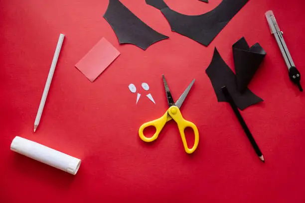 Photo of How to make bat out of paper at home. Hands making craft out of paper. Step by step photo instruction. Step 9. Eyes and fangs ready. Children DIY art project