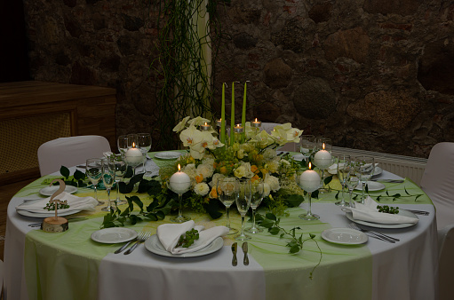 Decorated table with table compositions and burning candles, green, white
