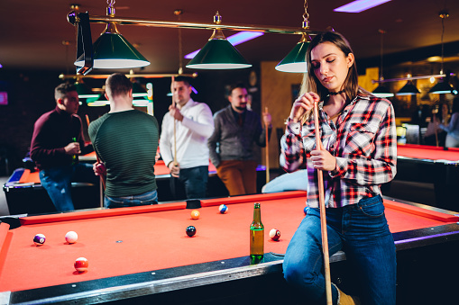 Young Caucasian beautiful woman sitting on pool table.