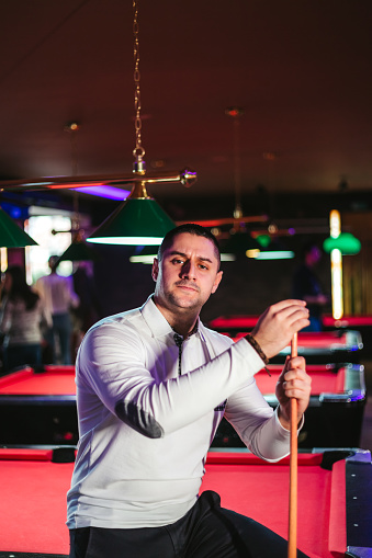 Young Caucasian handsome man playing snooker.