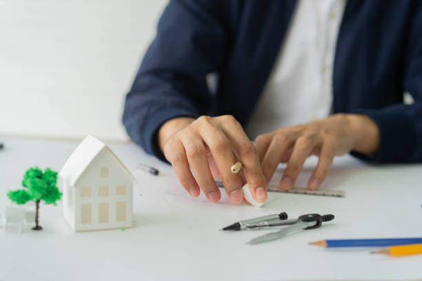 nahaufnahme architekt mann hand mit eraser, um skizze lineal zu löschen, nachdem fehler aus der zeichnung arbeit über immobilien-wohnungen und gebäude projekt am bürotisch für arbeitskonzept zu machen - business construction eraser blueprint stock-fotos und bilder