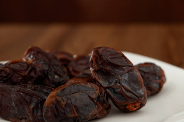 istock seedless dates on white plate and wooden background 1267367383