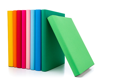 Front view of rainbow colored books standing on white background. The composition is at the left of an horizontal frame leaving useful copy space for text and/or logo at the right.High resolution 42Mp studio digital capture taken with SONY A7rII and Zeiss Batis 40mm F2.0 CF lens