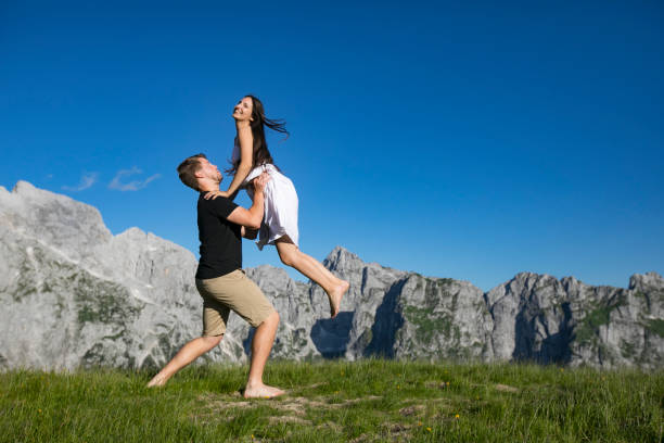 istock Boyfriend Catching Happy Girlfriend on Meadow in Mountains 1267368239