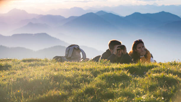 istock Young Adult Couple Lying on Meadow in Mountains and Using Binoculars 1267368241