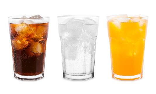 Glasses of soda drinks with ice cubes - orange, lemon lime and cola isolated on white background