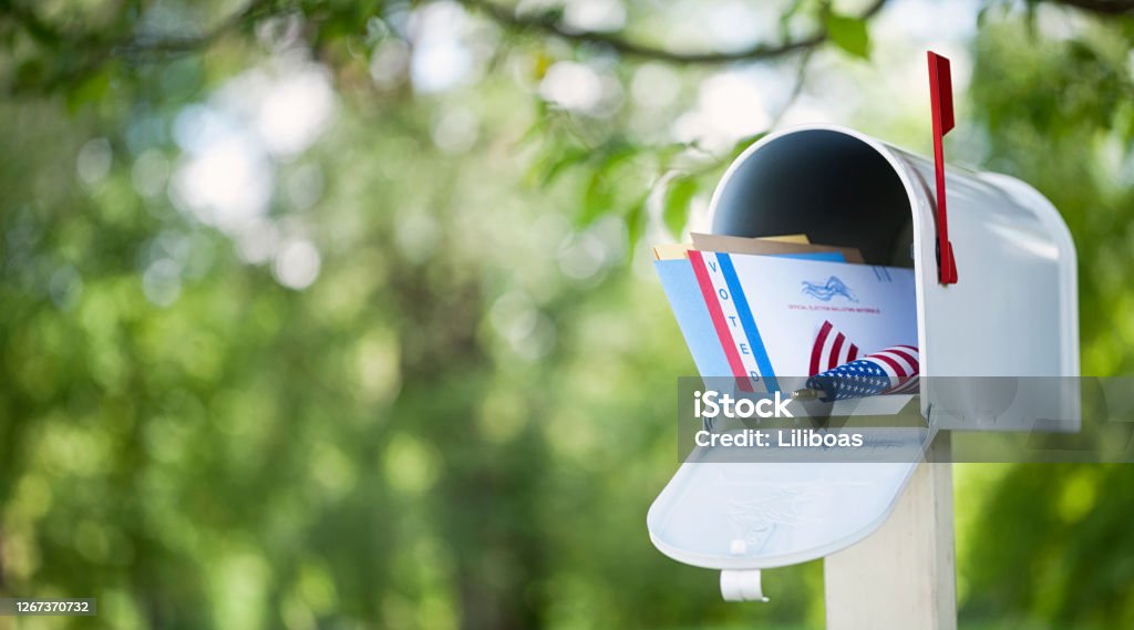 Voting By Mail Concept Voting by mail concept. Absentee ballot envelope in a mailbox against a defocused nature background. Mail Stock Photo