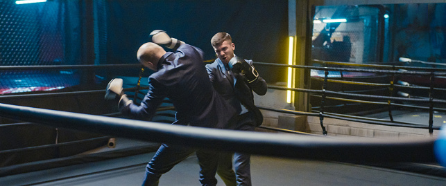 Men in elegant suit fighting in boxing gloves. Rough fight. Choking