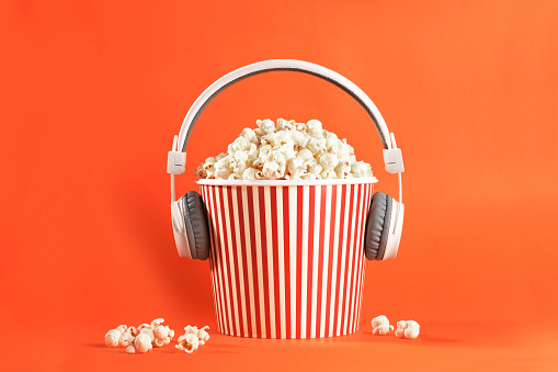 Popcorn with the headphone, a headphone plugged into the popcorn box, concept of entertainment