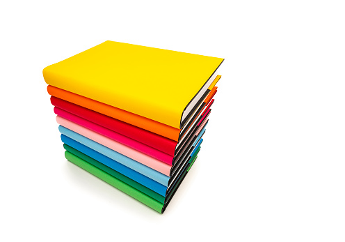 High angle view of rainbow colored books arranged in a stack isolated on white background. Useful copy space available for text and/or logo. High resolution 62Mp studio digital capture taken with SONY A7rII and Zeiss Batis 25mm F2.0 lens