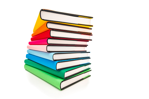 Wide angle front view of rainbow colored books arranged in a stack isolated on white background. The composition is at the left of an horizontal frame leaving useful copy space for text and/or logo at the right.High resolution 65Mp studio digital capture taken with SONY A7rII and Zeiss Batis 25mm F2.0 lens