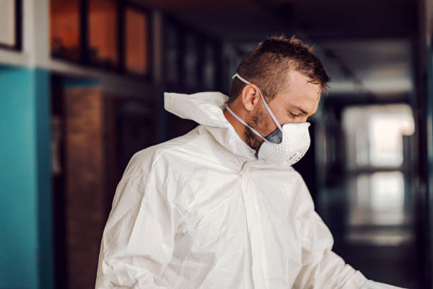 istock Worker in sterile white uniform standing in hallway in school after disinfecting. 1267383051