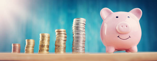 istock piggy bank with stacked coins on blue background 1267383266