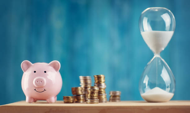 piggy bank with stacked coins and hourglass - stock market data insurance savings finance imagens e fotografias de stock