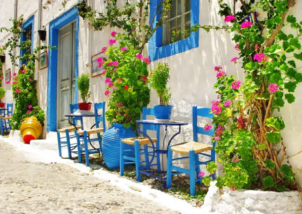 Charming colorful bars with typical wooden chairs in street of Kos island. Greece, Dodecanese