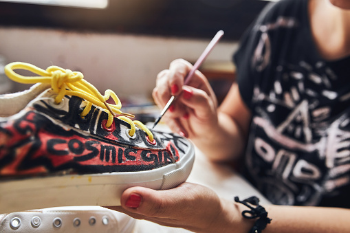 Artistic female artist in a workshop painting and decorating sneakers.