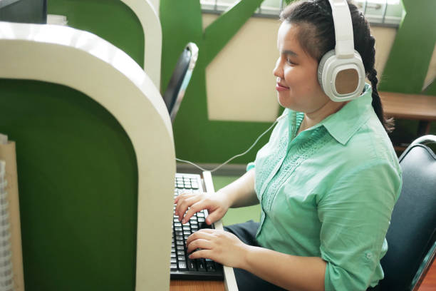 Disability young blind person happy woman in headphone typing on computer keyboard working in creative workplace office. Disability young blind person happy woman in headphone typing on computer keyboard working in creative workplace office. blindness stock pictures, royalty-free photos & images