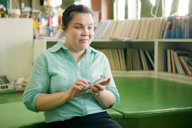 Asian young blind person woman using smart phone with voice accessibility for persons with disabilities in creative workplace. Asian young blind person woman using smart phone with voice accessibility for persons with disabilities in creative workplace. blindness stock pictures, royalty-free photos & images